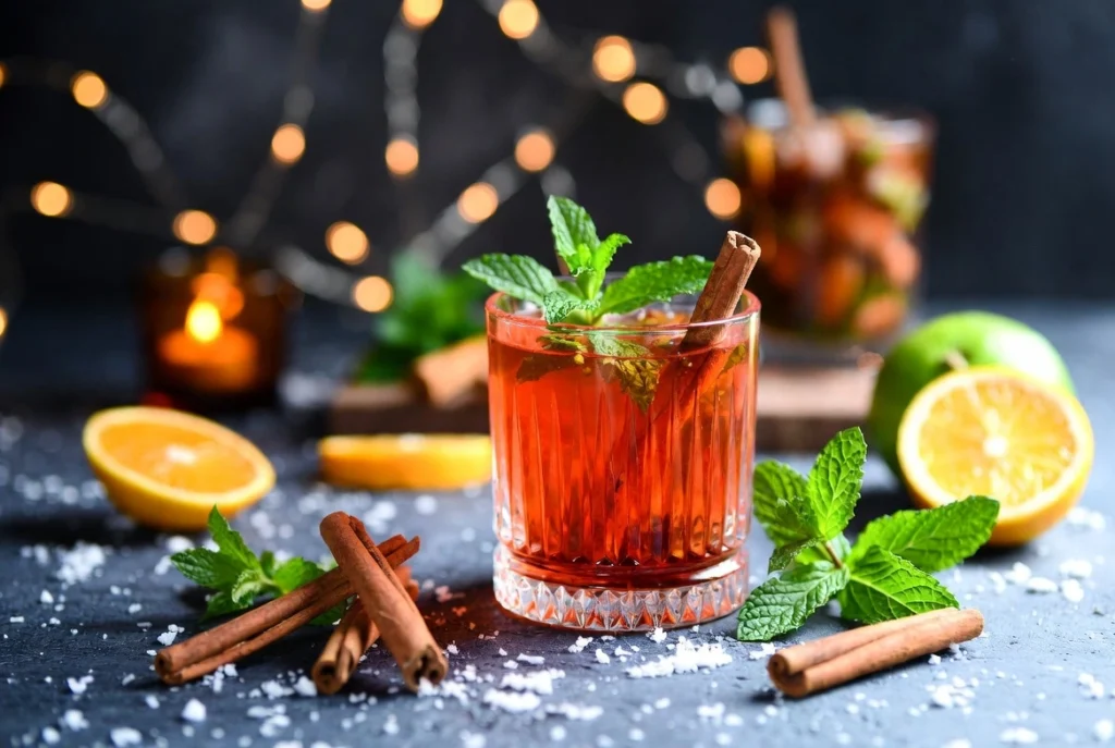 Vibrant herbal mocktails ingredients by Herba Organica including hibiscus flowers, peppermint leaves, lavender, rose petals, and lemon balm arranged on a summer table with fresh fruit and ice cubes, bright and colorful."