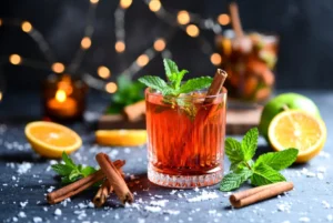 Vibrant herbal mocktails ingredients by Herba Organica including hibiscus flowers, peppermint leaves, lavender, rose petals, and lemon balm arranged on a summer table with fresh fruit and ice cubes, bright and colorful."